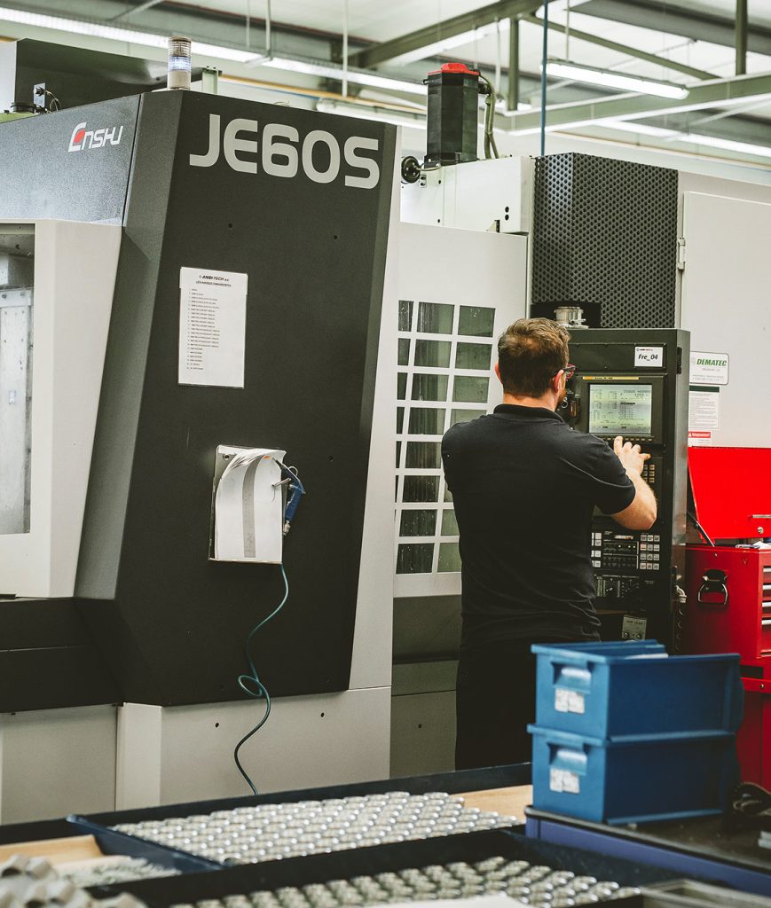 An employee programming an ENSHU JE60S vertical milling machine in the ANBI-TECH shop floor – CNC milling