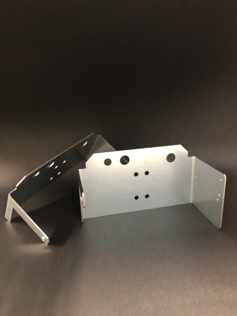 Two bent components made from light steel sheet with numerous mounting holes, arranged against a black background.