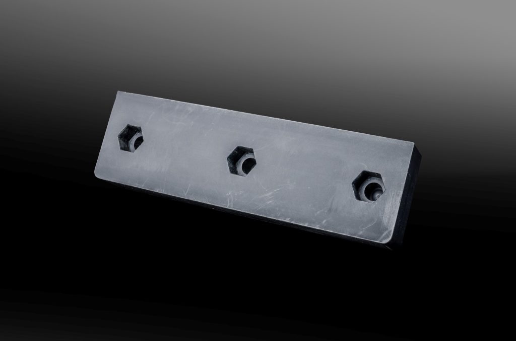 Black rectangular plastic plate with three hexagonal screw sockets against a dark background.