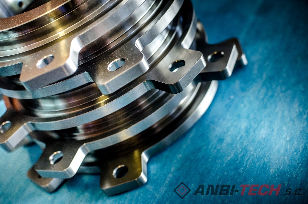 Precisely machined metal components with lugs and mounting holes, stacked one on top of another against a blue background.