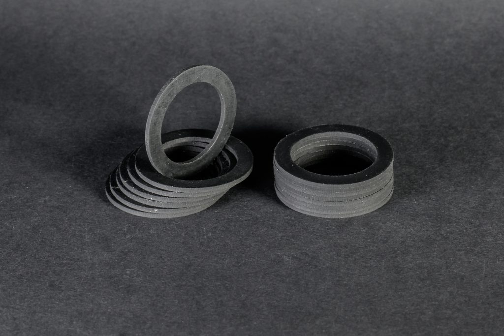 Two stacks of black, matte flat rings stand on a dark grey background, with one disc propped up vertically.