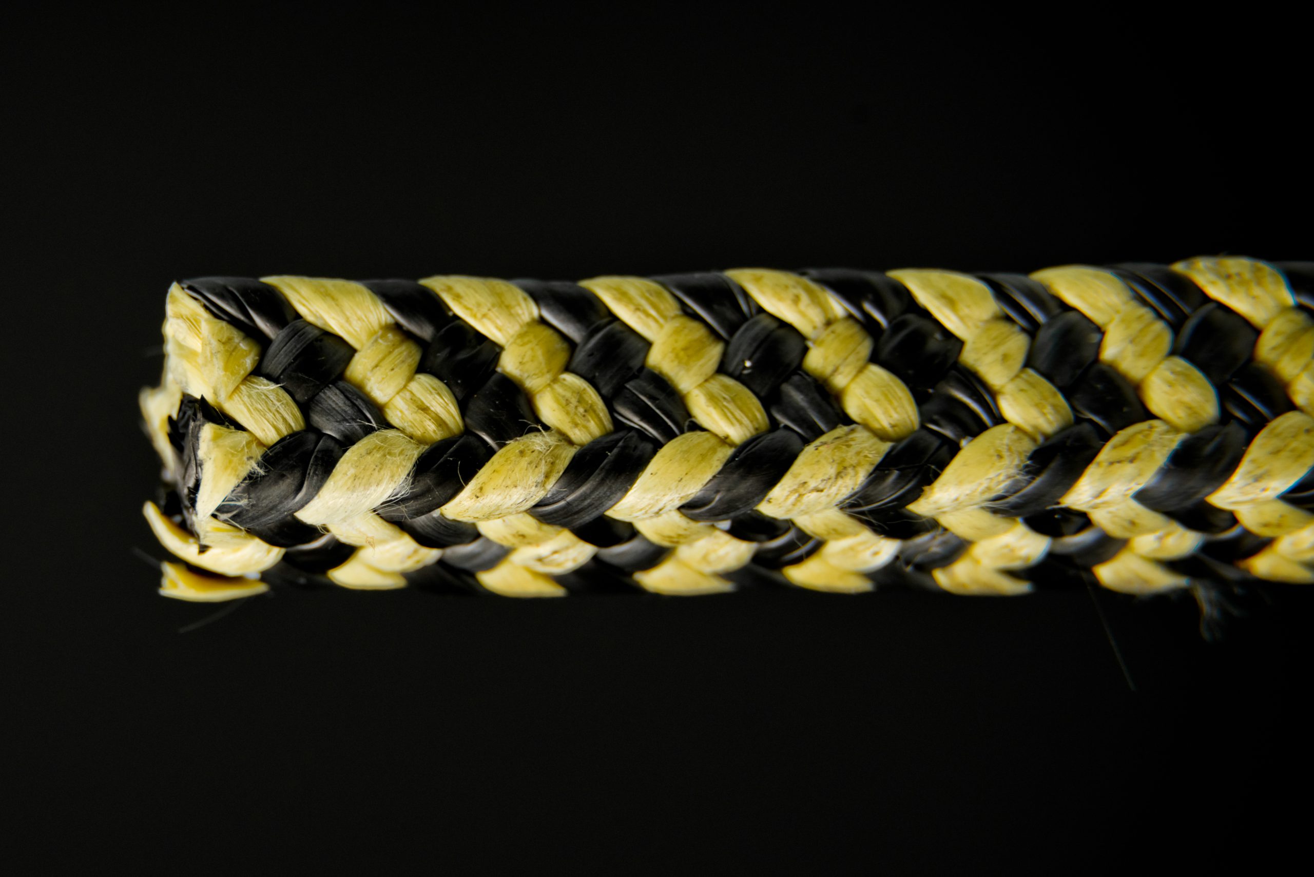 Macro of yellow-and-black composite packing, aramid Kevlar plus graphite - alternating braid