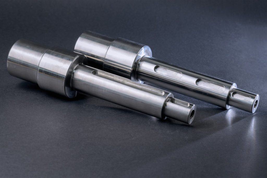 Two precisely machined stepped metal shafts with keyways, placed against a dark background.