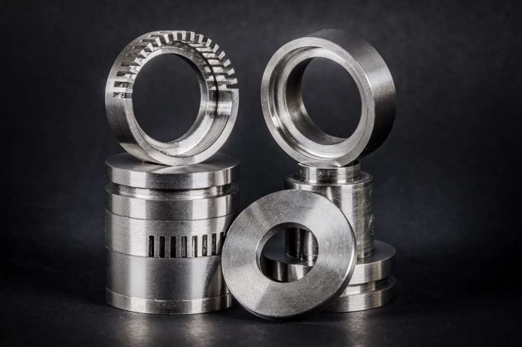 Gleaming silver metal components standing against a black background, arranged in two tall stacks, with rings on top and beside them.