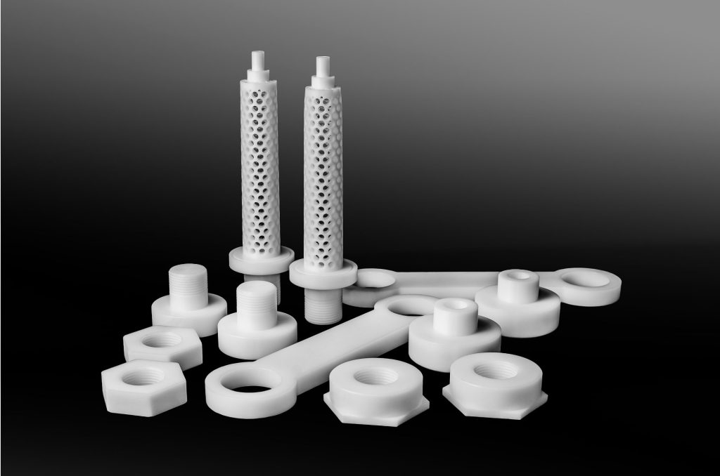 White technical components against a black background, including perforated tubes with pins and threaded nuts.
