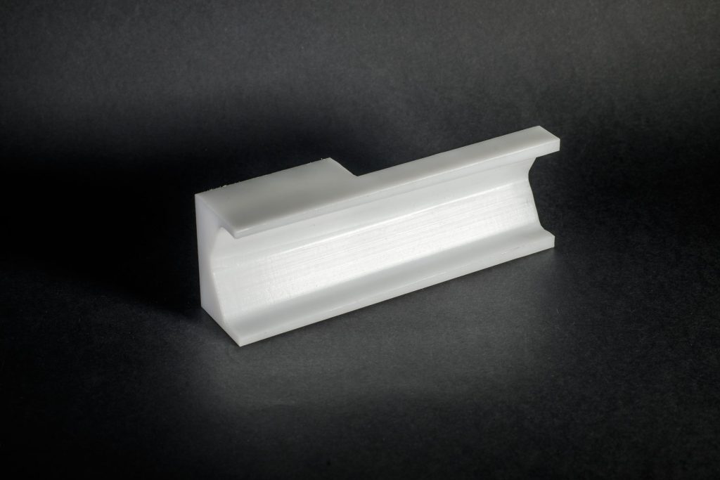 White plastic print with a curved recess lying on a black surface under side lighting.