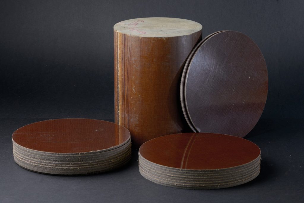 Brown tall cylinder, an upright plate and two low discs with visible layers on smooth edges.