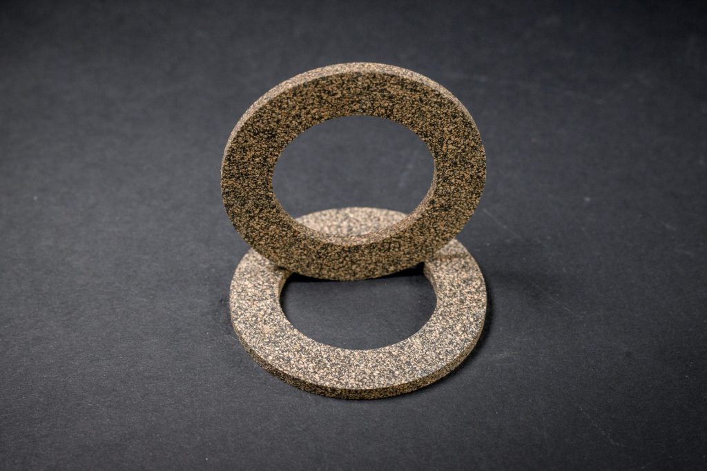Two flat brown rings with a hole in the middle, one standing and one lying on a dark background, showing their grainy texture.