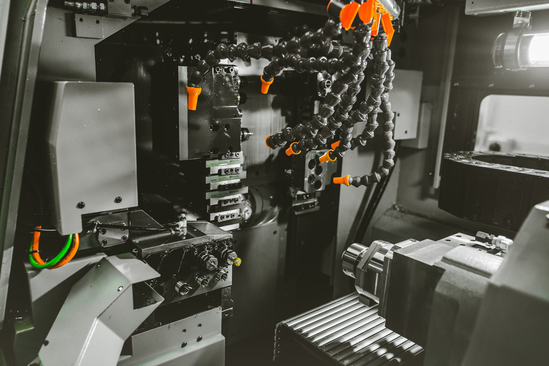 Interior of a CNC machine tool with a spindle unit, cutting tools and flexible coolant hoses.